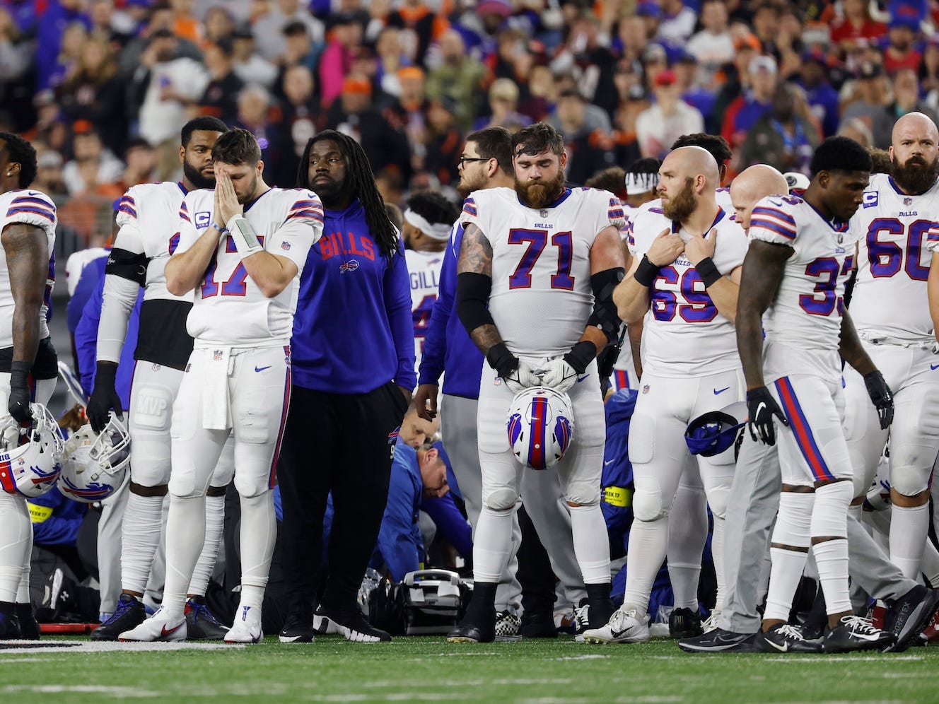 Spieler der Buffalo Bills umringen ein medizinisches Team, das sich um Damar Hamlin nach seinem Herzstillstand auf dem Footballfeld kümmert.