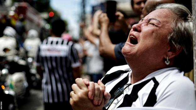Ein emotionaler Pele-Fan weint, als sein Körper durch die Straßen von Santos getragen wird