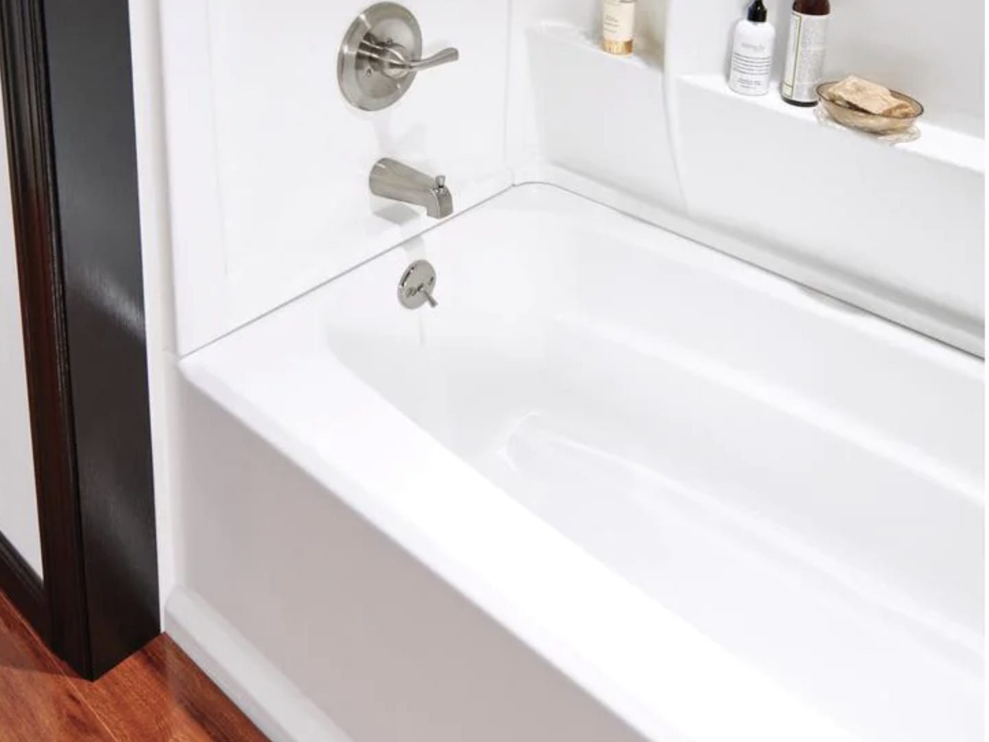 Nahaufnahme einer weißen Alkoven-Badewanne mit Badeprodukten an der Wand