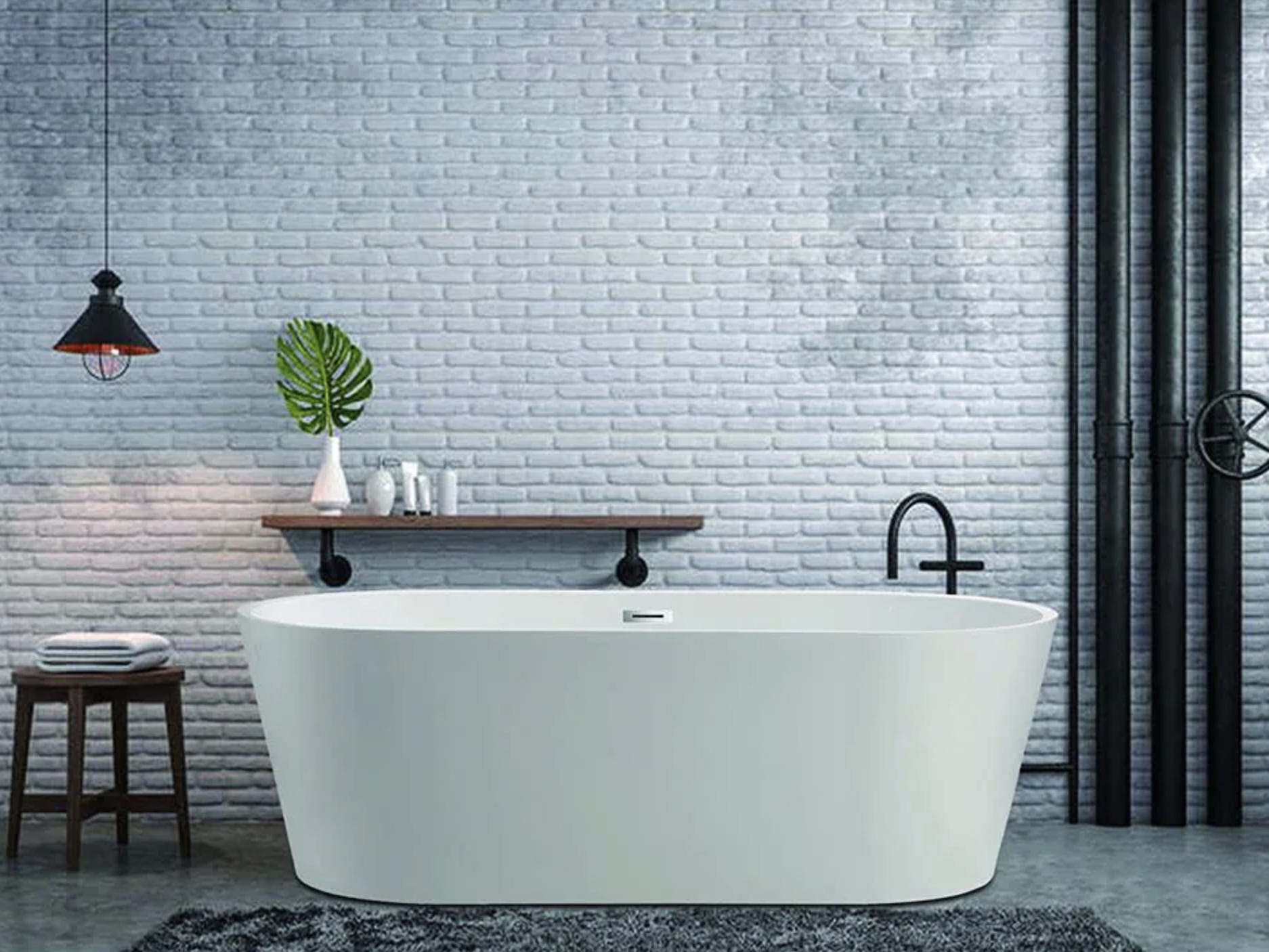 Weiße freistehende Badewanne vor einer gefliesten Wand eines modern anmutenden Badezimmers