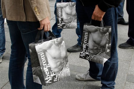 Menschen halten Abercrombie-Taschen mit hemdlosen Männern darauf