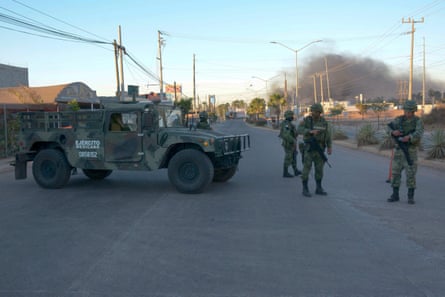 Soldaten stehen während der Operation zur Festnahme von Guzmán neben brennenden Fahrzeugen auf einer Straße Wache