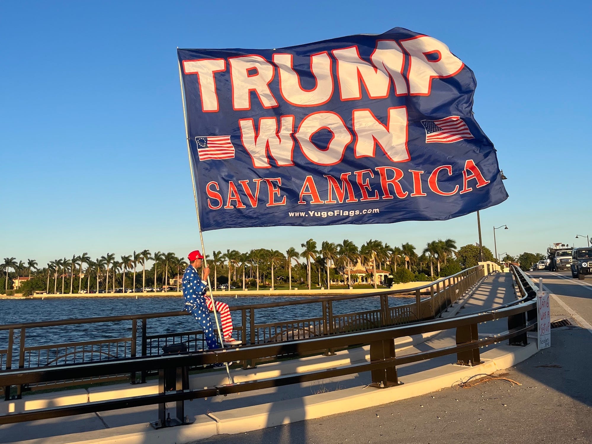 Trump-Unterstützer hält eine Pro-Trump-Flagge mit Mar-a-Lago im Hintergrund.