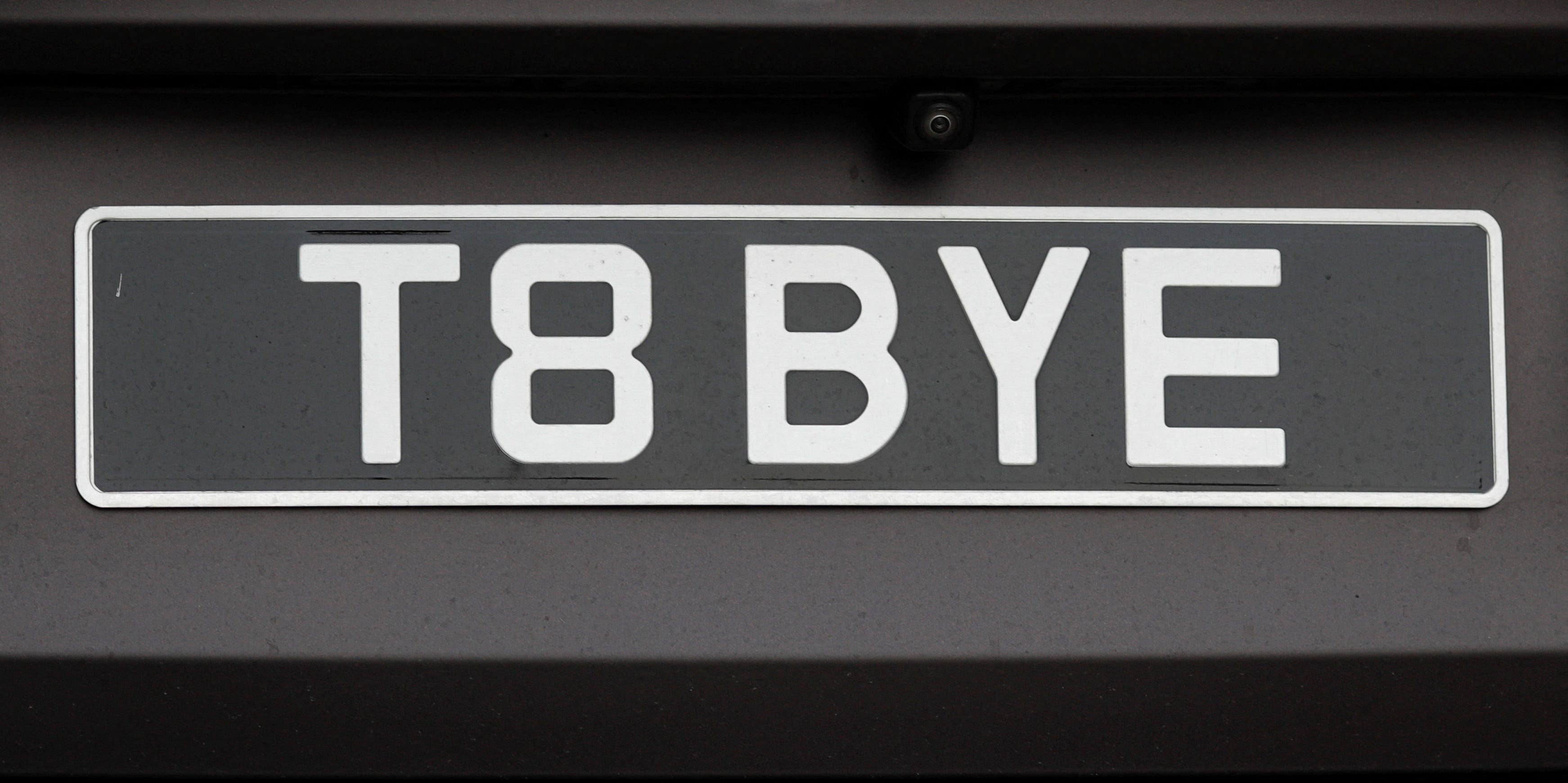 Ein Autokennzeichen mit der Aufschrift T8 BYE ist zu sehen, während rumänische Beamte die beschlagnahmten Autos aus dem Tate-Gelände zu einem unbekannten Lagerort aus Voluntari, Ilfov, Rumänien, transportieren