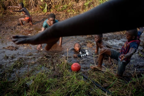 Kinder spielen mit einem Fußball auf einem sehr schlammigen Feld