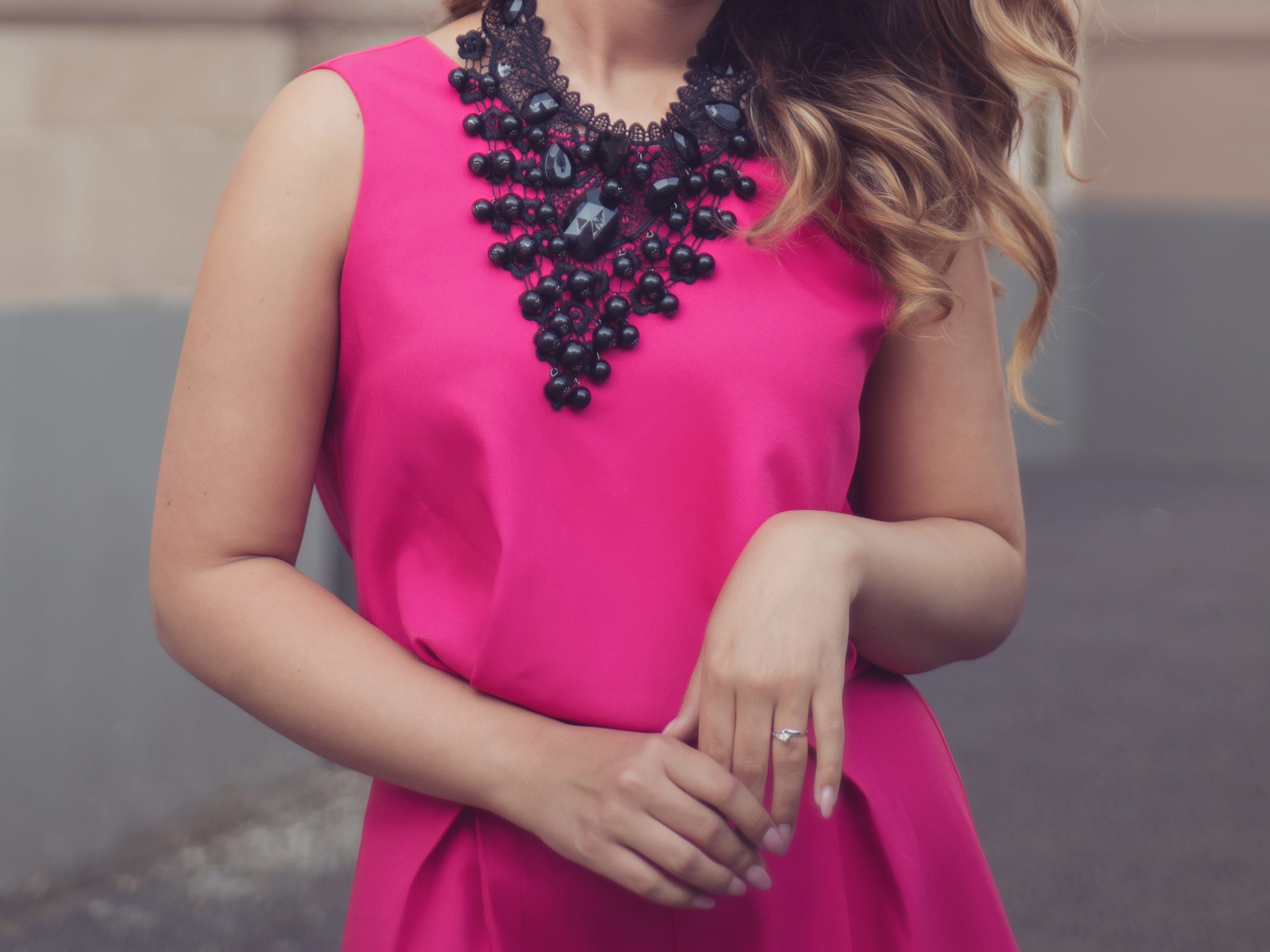 Person, die ein rosafarbenes Kleid mit einer schwarzen Statement-Halskette trägt
