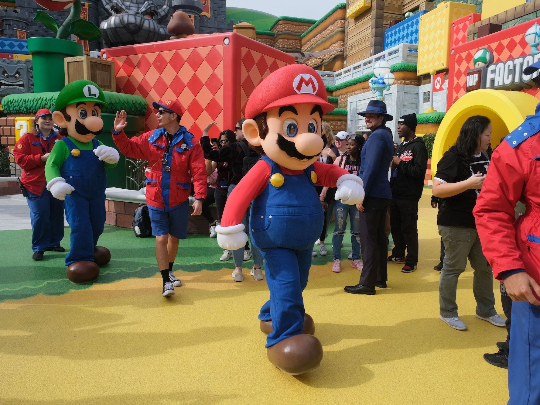 Mario und Luigi werden auf dem Weg zu einer Pause während einer Vorschau auf Super Nintendo World in den Universal Studios in Los Angeles, Kalifornien, am 13. Januar 2023 durch die Menge eskortiert.
