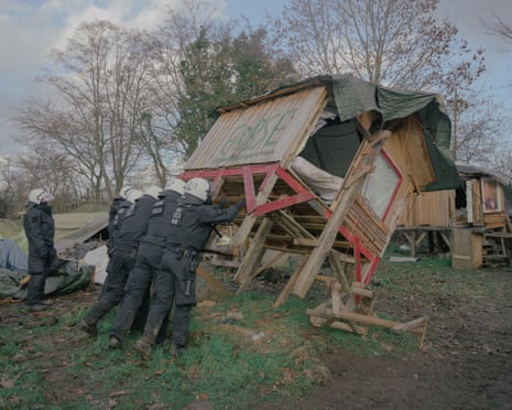 Polizisten zerstören ein Holzhaus