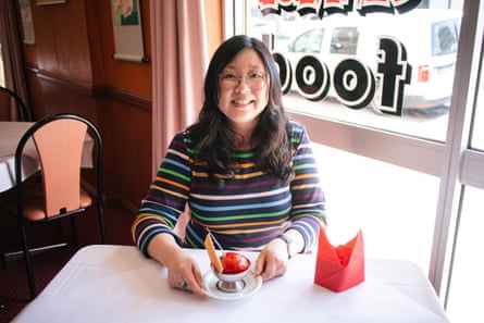 Moderatorin Jennifer Wong, in einem bunt gestreiften Hemd, sitzt an einem weiß gedeckten Tisch mit einer Schüssel frittiertem Eis.