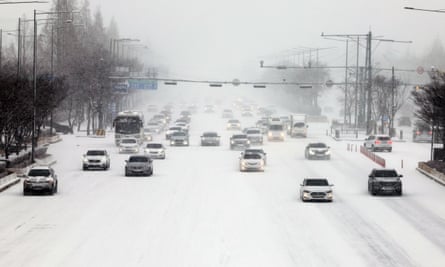 Autos bewegen sich am Dienstag langsam auf einer Straße inmitten von starkem Schneefall in Gwangju, Südkorea.