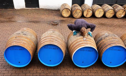 Ein Mitarbeiter beugt sich über eines in einer Reihe von Fässern, die darauf warten, in der Glenturret-Brennerei gefüllt zu werden.