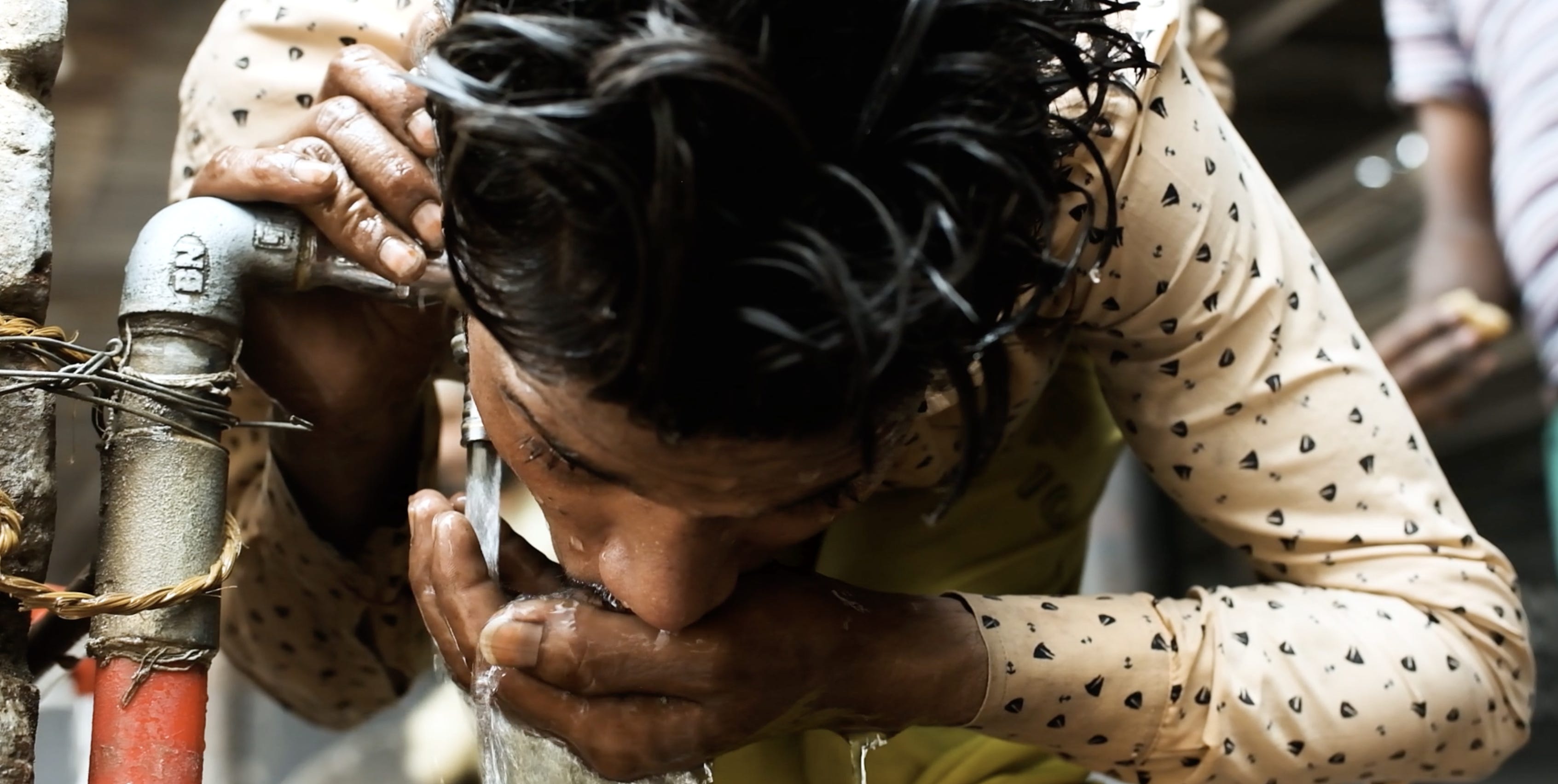 Ein Arbeiter trinkt Wasser direkt aus dem Wasserhahn