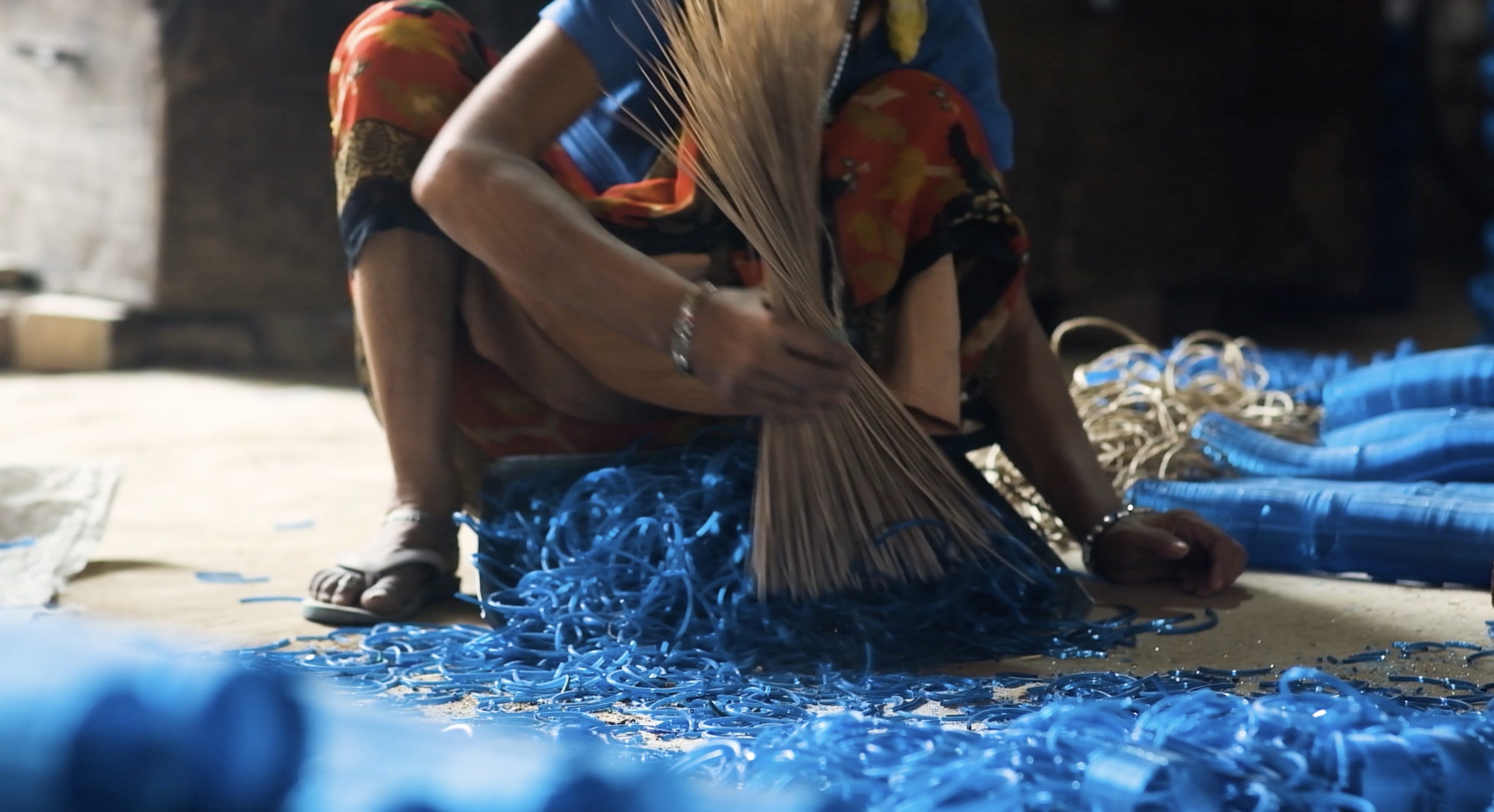 Eine Frau fegt leuchtend blaue zerbrochene Armreifen vom Boden