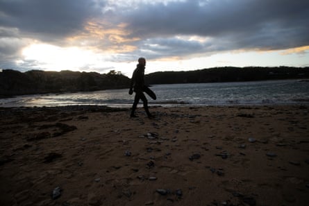 Freitaucher Callum Stewart läuft im ersten Licht der Morgendämmerung über einen Strand.