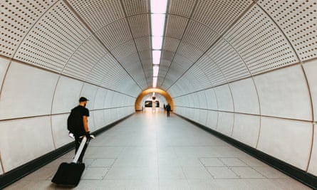Verschwommene Bewegung eines Pendlers, der in einem Tunnel an der U-Bahnstation Tottenham Court Road spaziert, umgeben von der modernen futuristischen Architektur der neuen Entwicklung der Elizabeth-Linie.