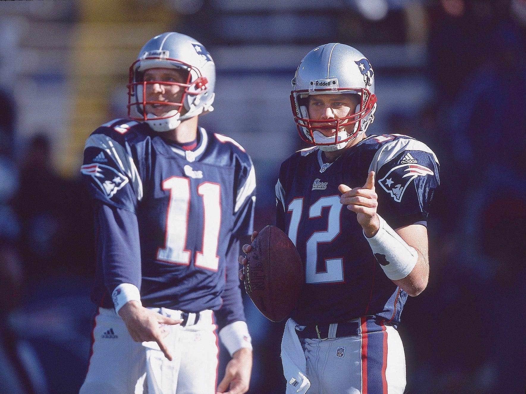 Tom Brady zeigt und hält einen Fußball, während er 2001 neben Drew Bledsoe steht.