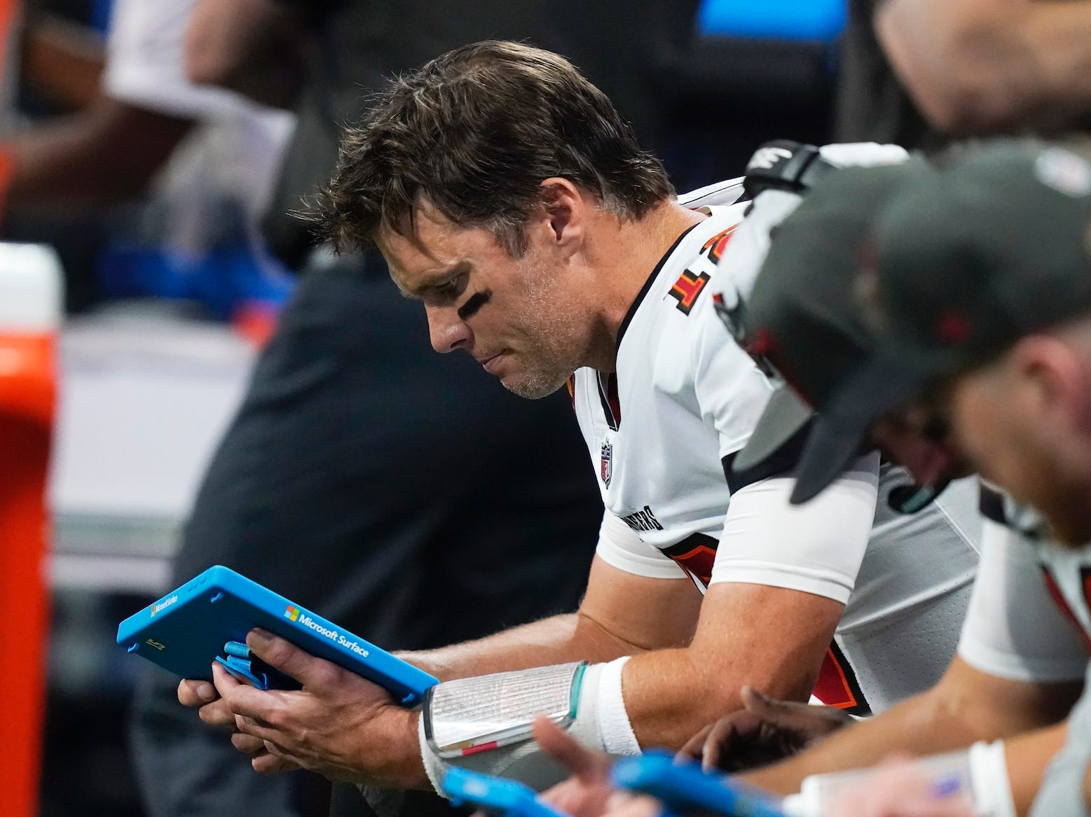 Tom Brady sitzt auf der Bank und schaut auf ein Tablet im Jahr 2021.
