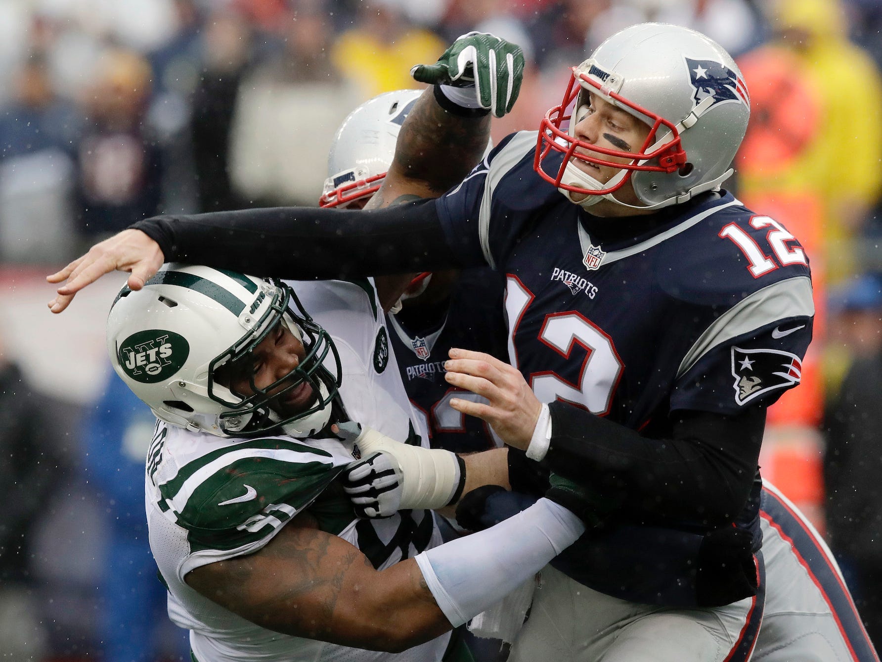 Tom Brady wirft den Ball, als er 2016 von Jets-Spielern getroffen wird.