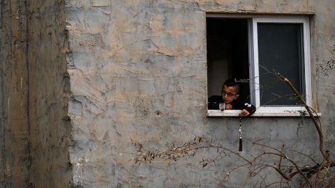 Ein Kind spielt an einem Fenster neben dem zerstörten Gebäude.