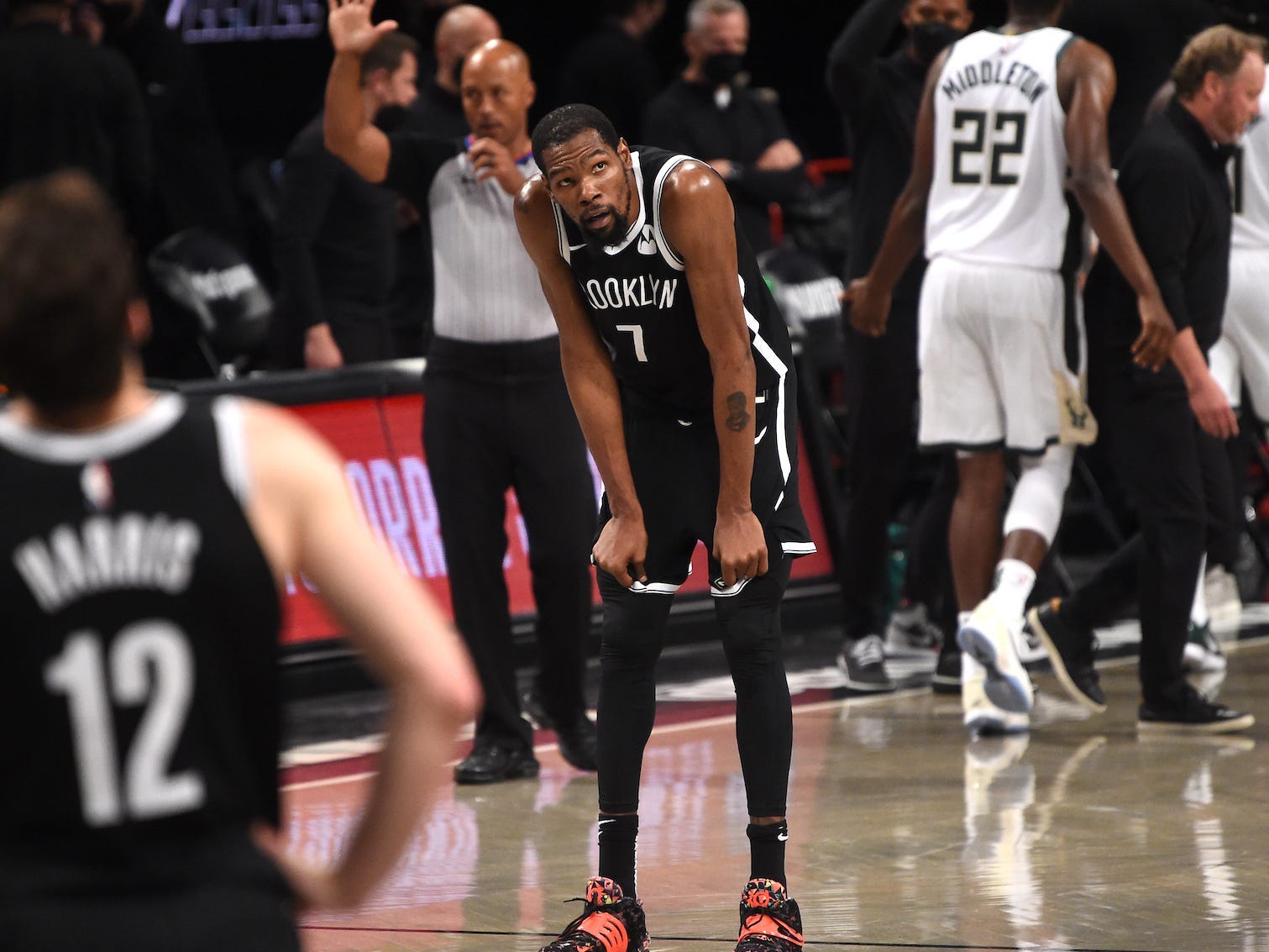 Kevin Durant stützt seine Hände auf seine Knie und sieht auf, während Nets and Bucks-Spieler während eines Spiels vom Platz gehen.