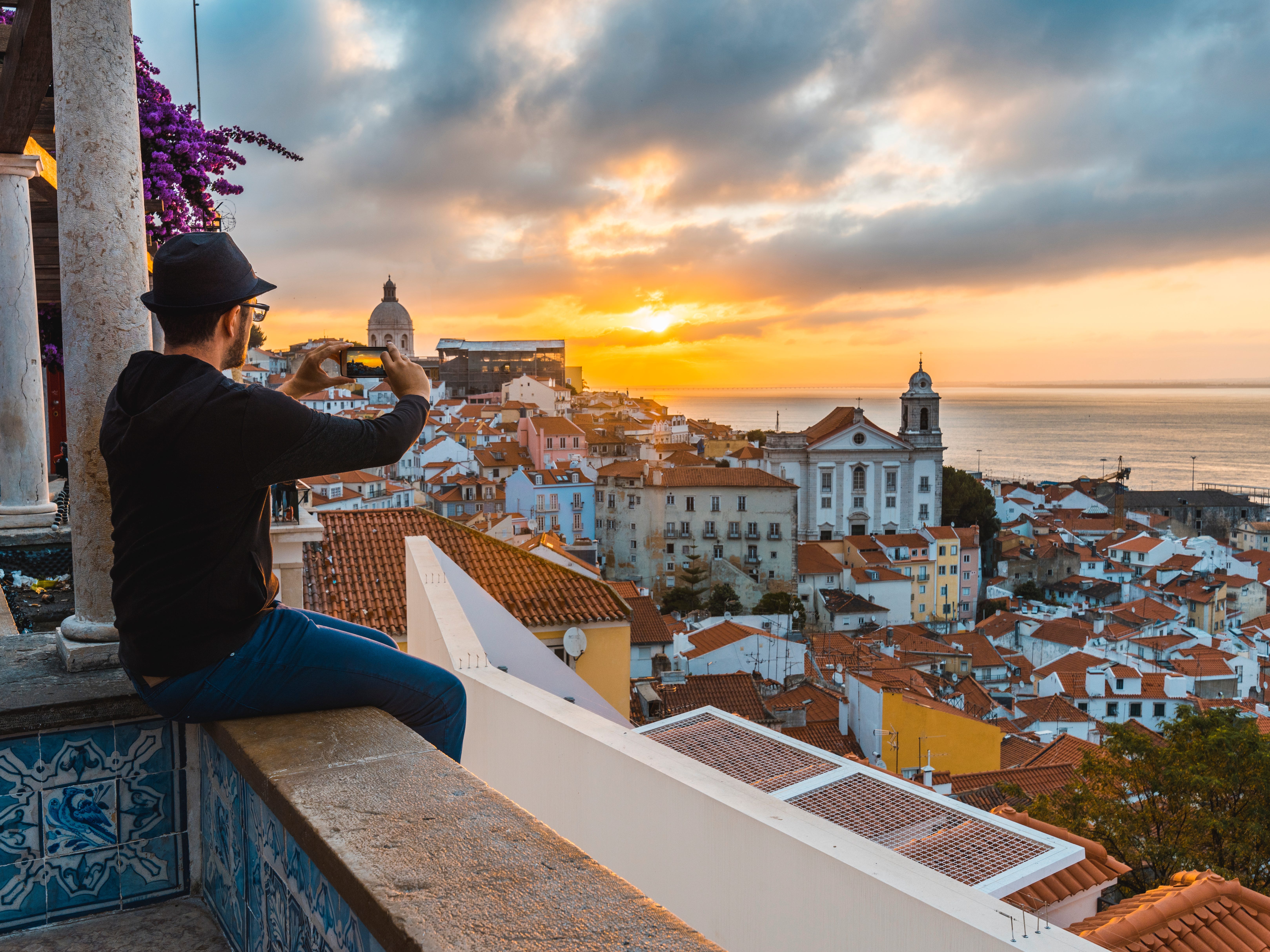 Ein Tourist fotografiert den Sonnenaufgang in Lissabon, Portugal, das als beste Stadt der Welt für Telearbeiter gilt.