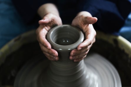 Hände einer Frau, die Keramik genießt.