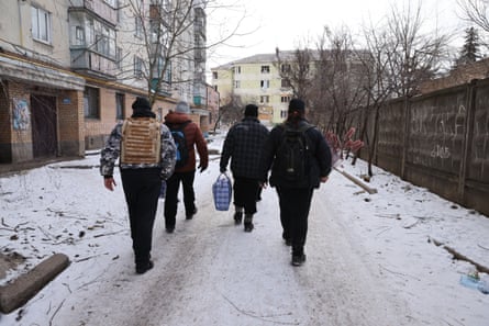 Menschen gehen auf einer schneebedeckten Straße in Bakhmut.