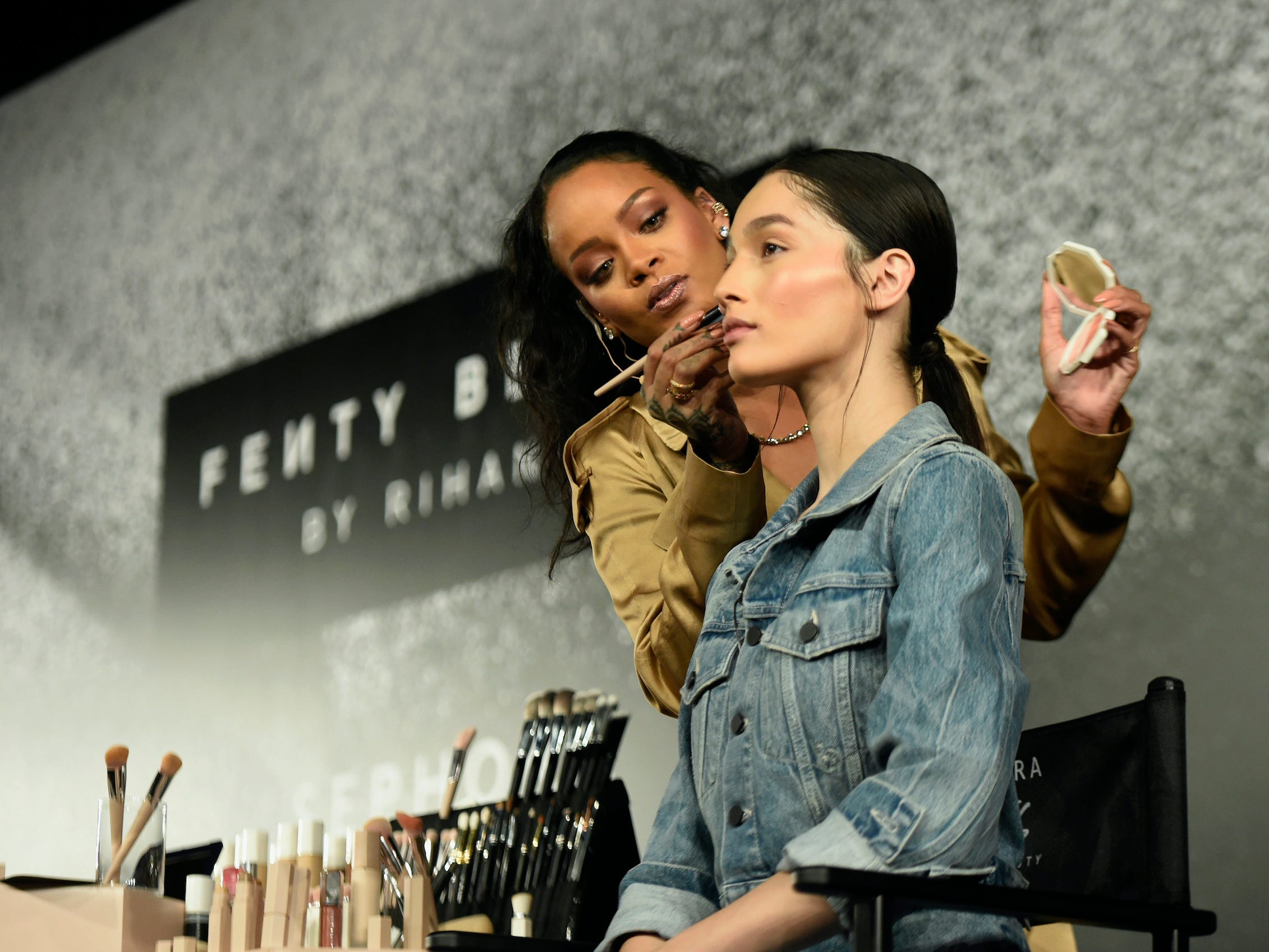 Rihanna schminkt ein Model auf der Bühne mit Fenty Beauty Make-up