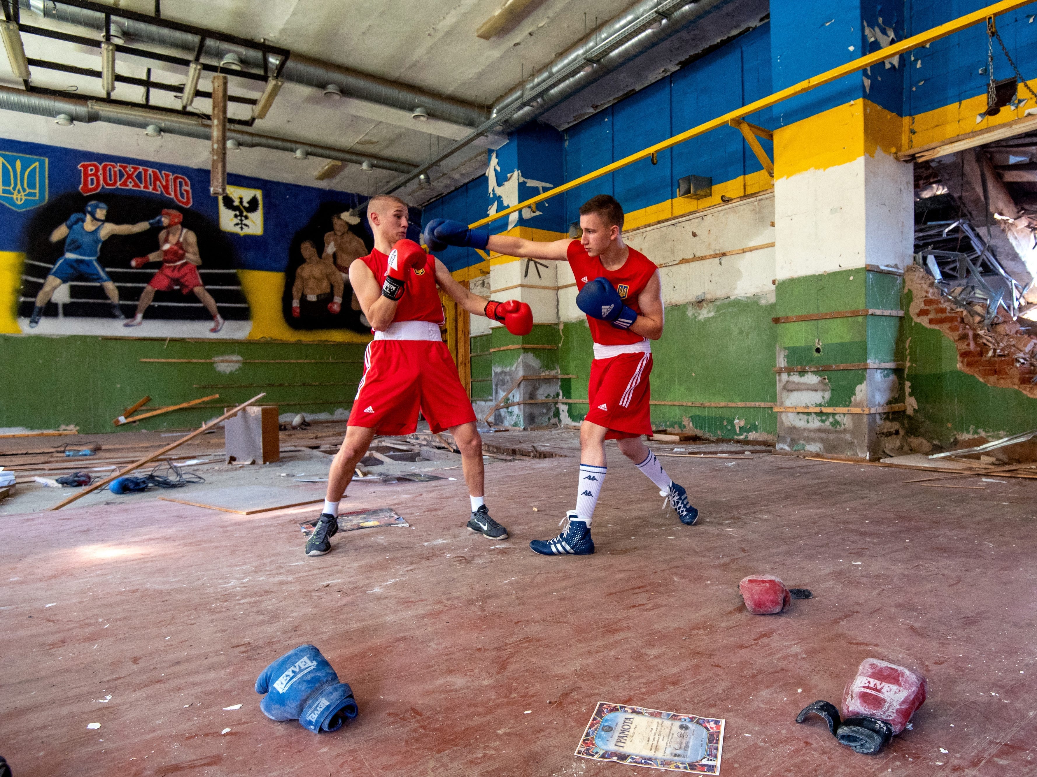Zwei Boxer trainieren in einer Boxhalle in Tschernihiw in der Nordukraine.  Die Halle hat ein klaffendes Loch in der Wand, nachdem sie von einer Rakete getroffen wurde.