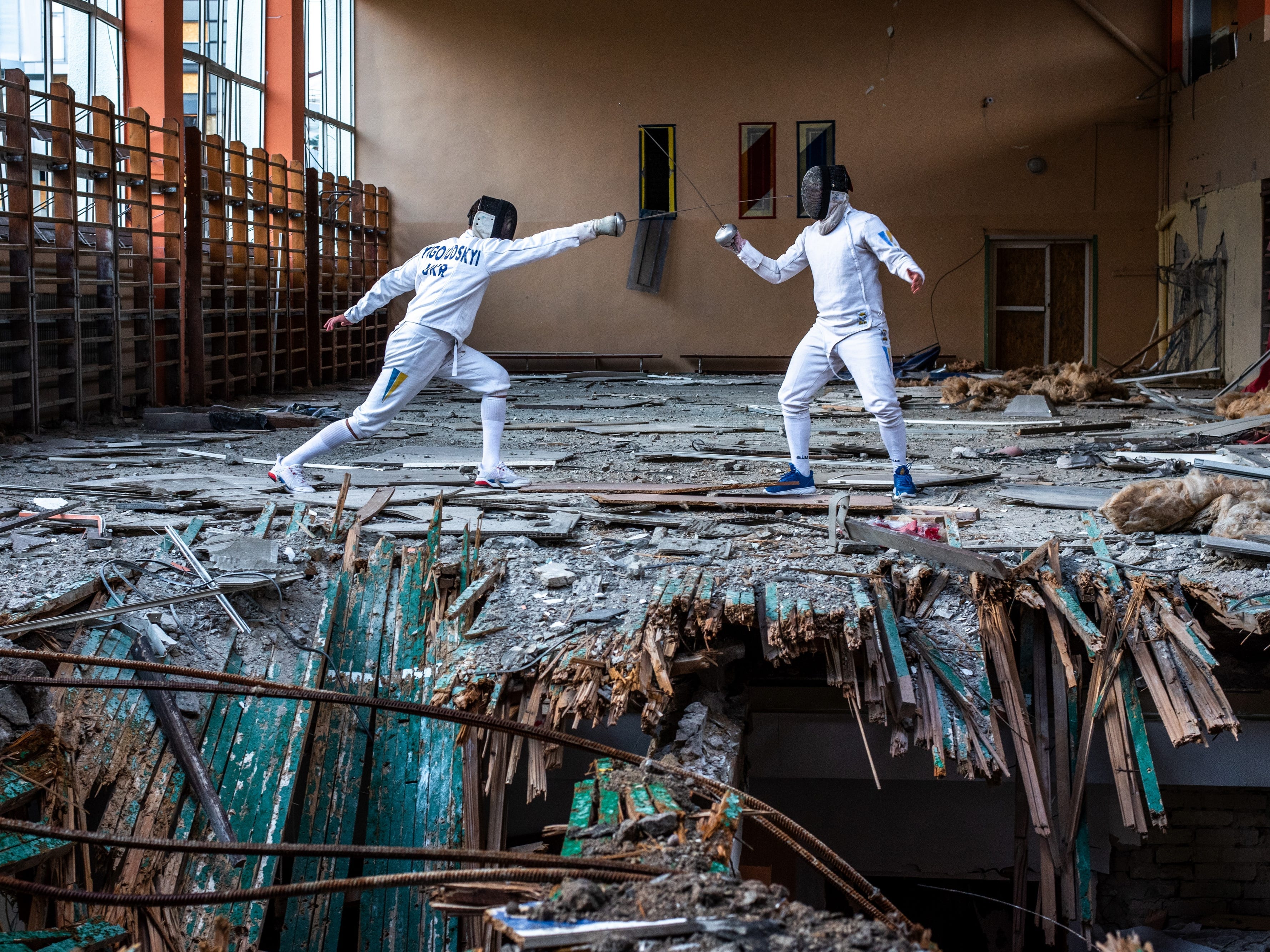Bildunterschrift: Fechter beim Training in einer zerstörten Halle in Charkiw mit eingebrochenem Boden.