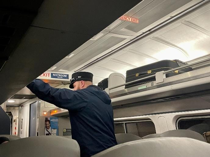 Zugbegleiter, der Gepäck auf die oberste Ebene des Amtrak-Zugs legt