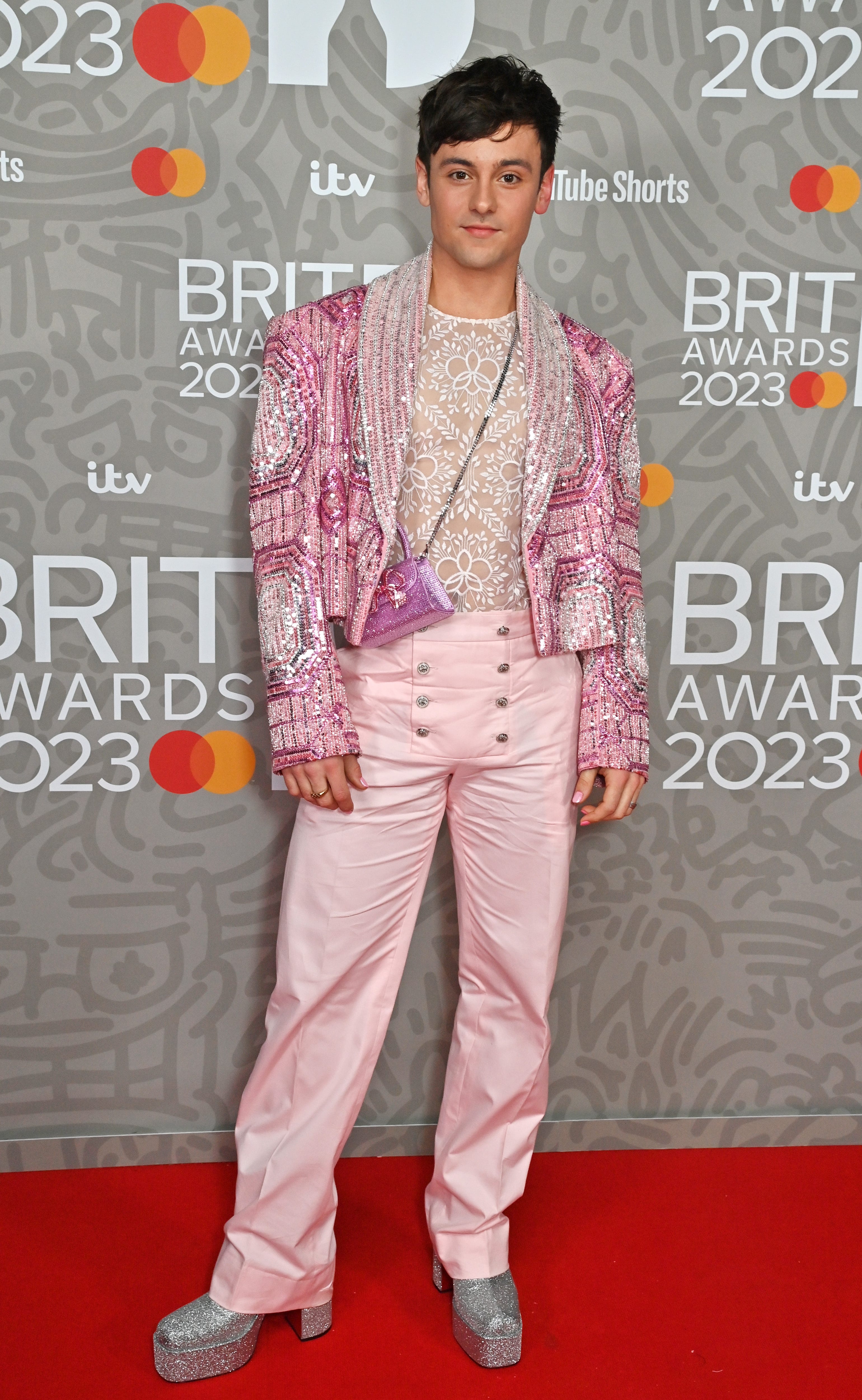 Tom Daley nimmt an den Brit Awards 2023 in rosa Hosen, einem transparenten Oberteil und einer rosa, verzierten Jacke teil.