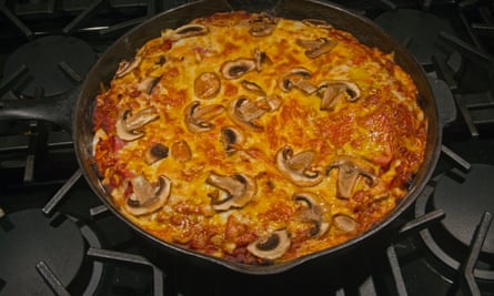 Backen Sie die Pizza doppelt, indem Sie sie einige Minuten in einem Bratplan geben, bevor Sie sie in den Ofen geben
