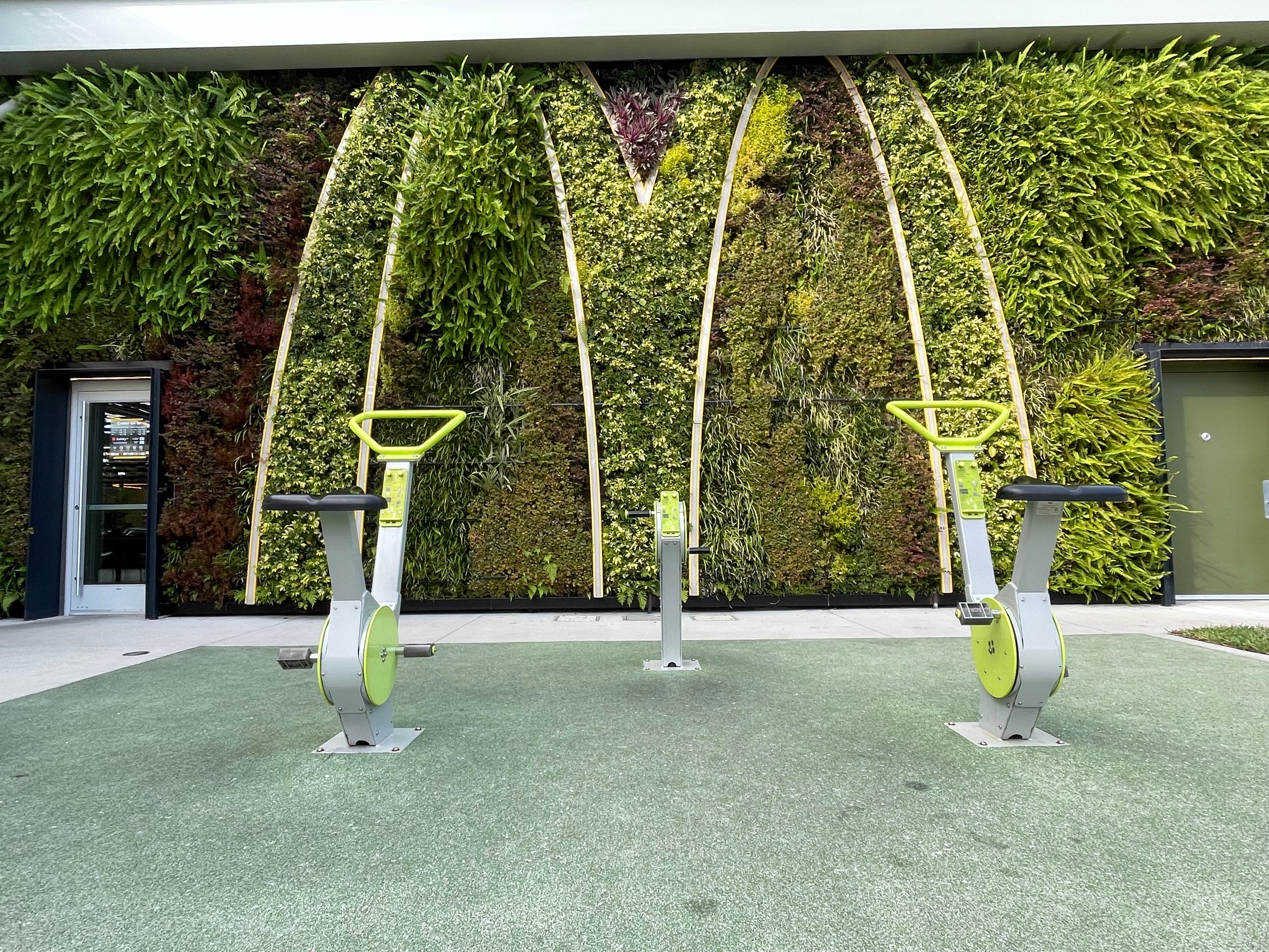 Pflanzenwand mit Heimtrainern davor außerhalb der Mcdonalds in Disney World