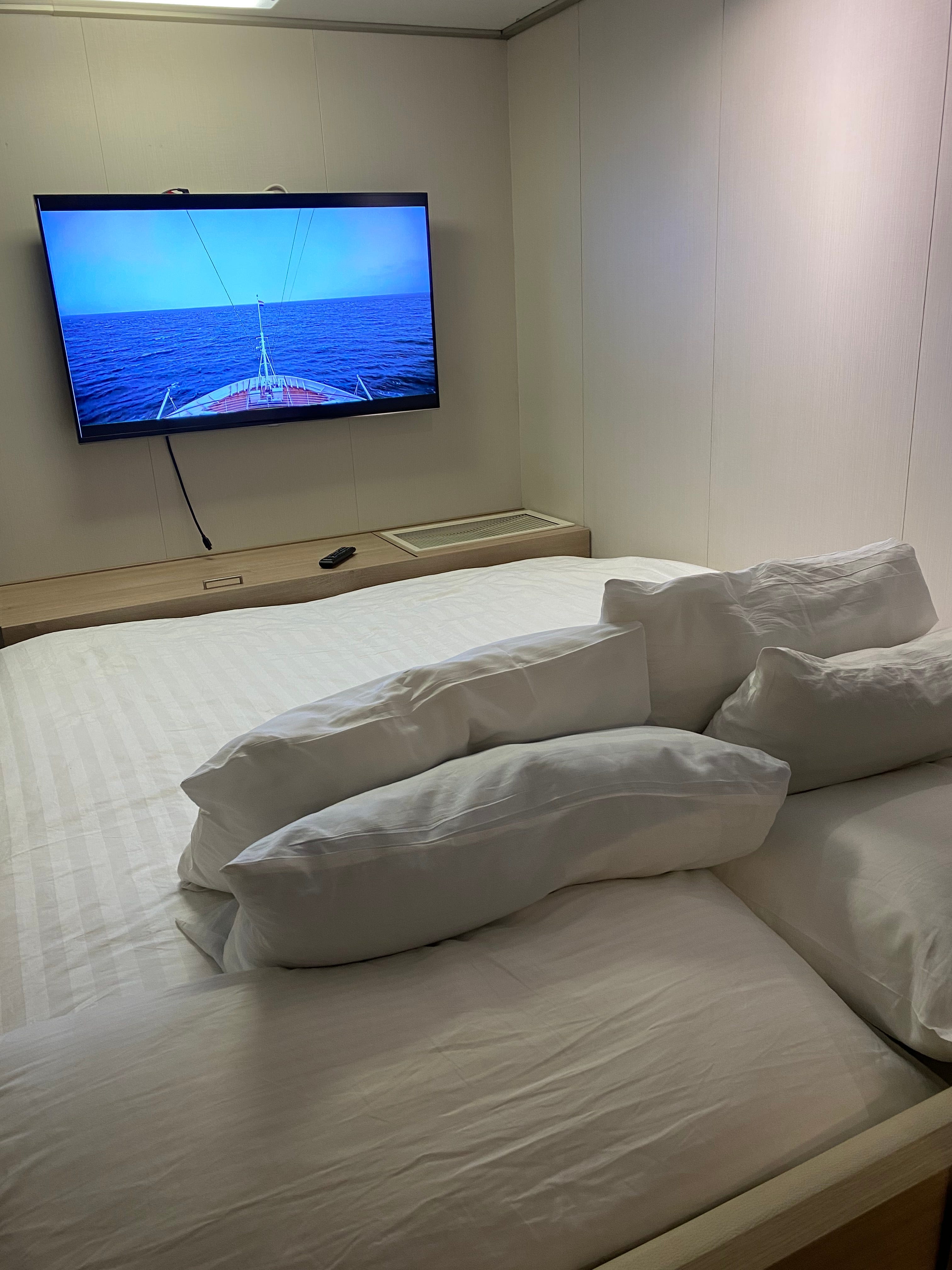 Bett mit Blick auf den Fernseher an der Wand