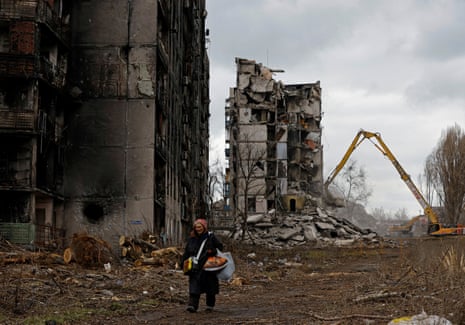 Eine Frau geht im besetzten Mariupol an zerstörten Wohnblocks vorbei.
