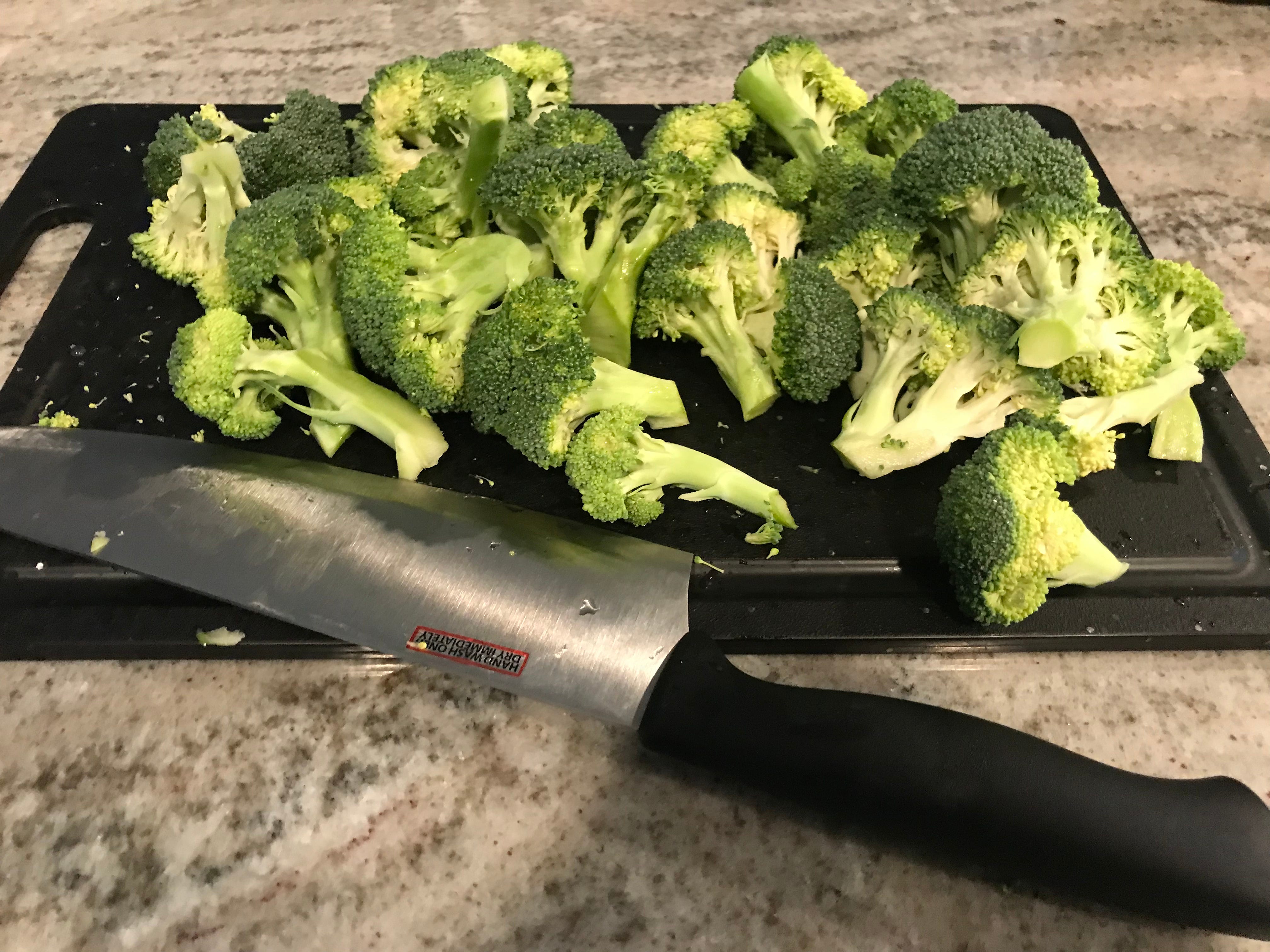 Brokkoli und Messer sitzen auf einem Schneidebrett