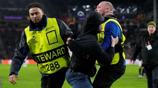 Pitch Invasor wird während PSV gegen Sevilla von Stewards vom Platz eskortiert