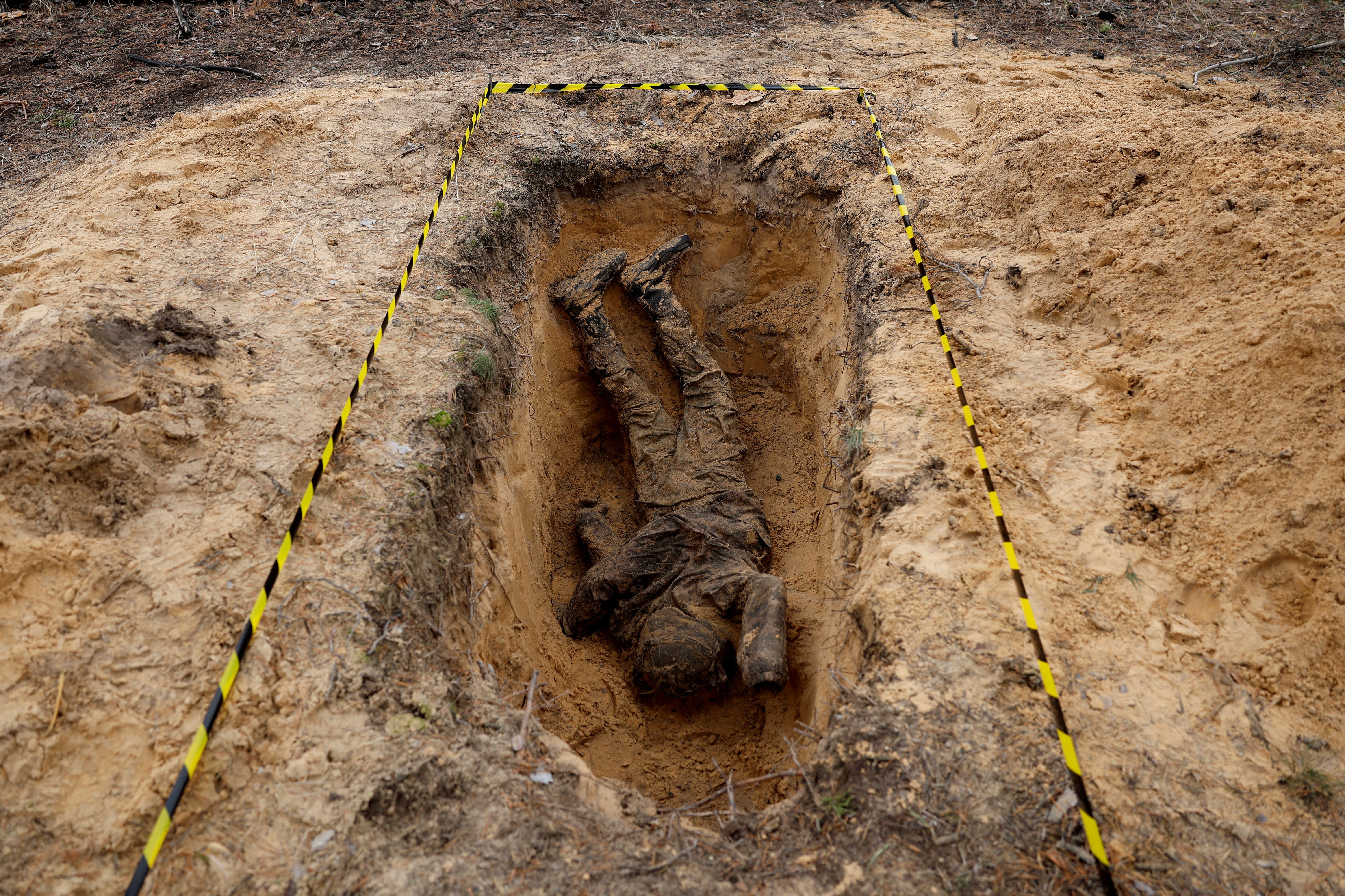 Eine Leiche wird in einem ausgegrabenen Grab gesehen.