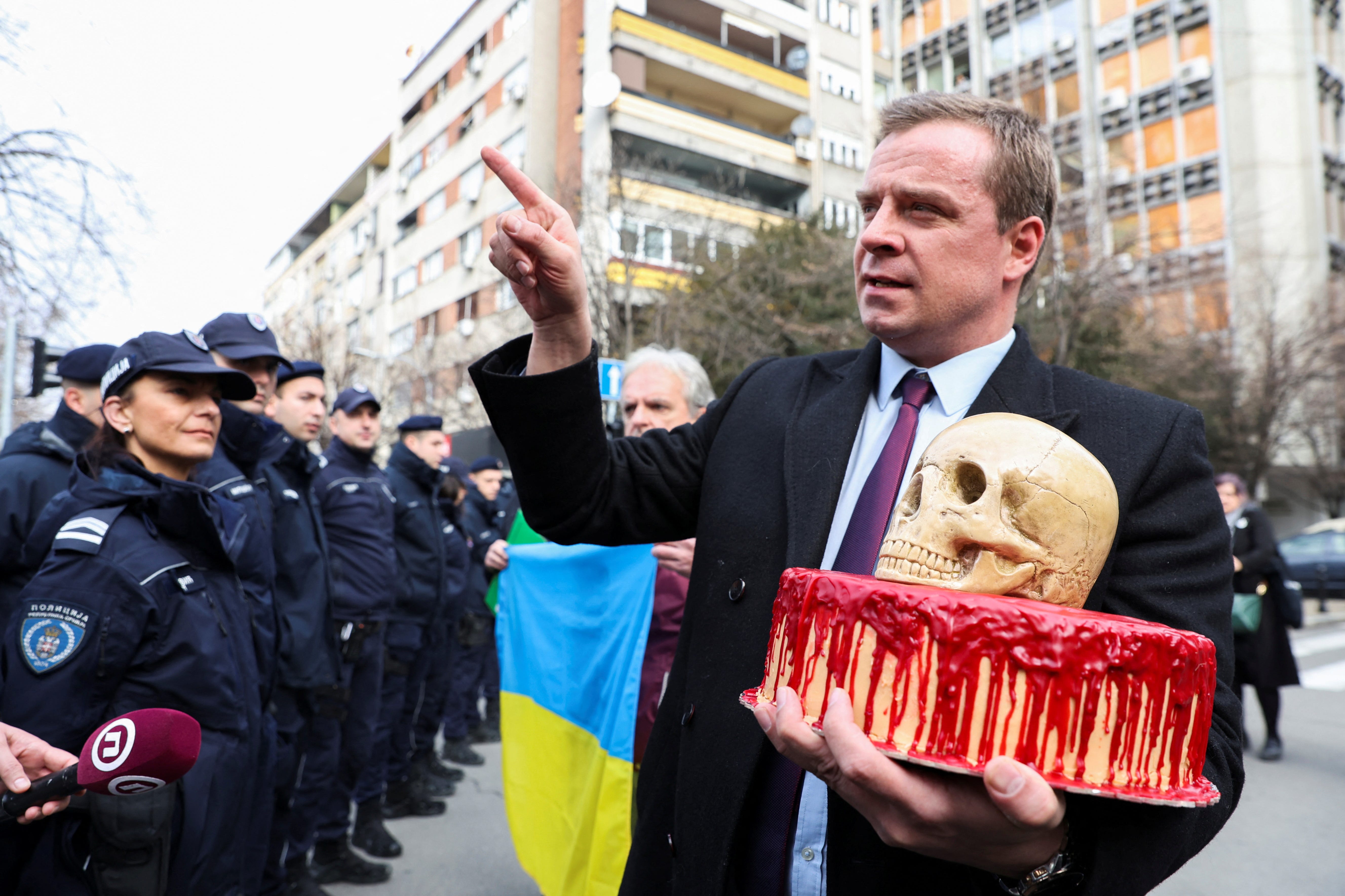 Cedomir Stojkovic, ein pro-ukrainischer Aktivist in Serbien, liefert einen blutigen Kuchen und einen Schädel an die Polizei, die die russische Botschaft in Belgrad bewacht, am Jahrestag der russischen Invasion in der Ukraine in Belgrad, Serbien, 24. Februar 2023.