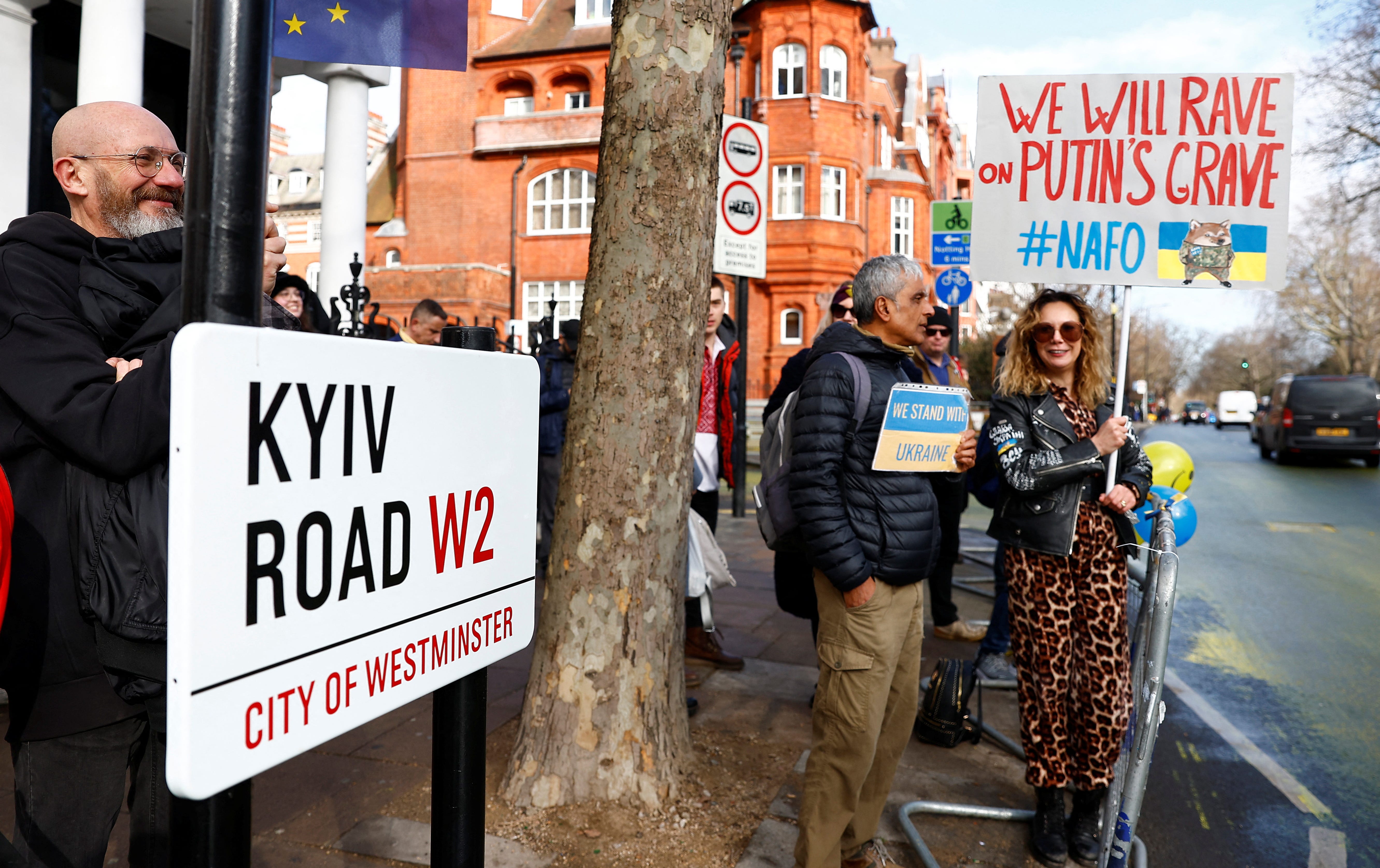 Anti-Putin-Demonstranten und Passanten stehen neben dem neu installierten Straßenschild Kyiv Road, das vom Stadtrat von Westminster gegenüber der russischen Botschaft in London, Großbritannien, am 24. Februar 2023 installiert wurde.
