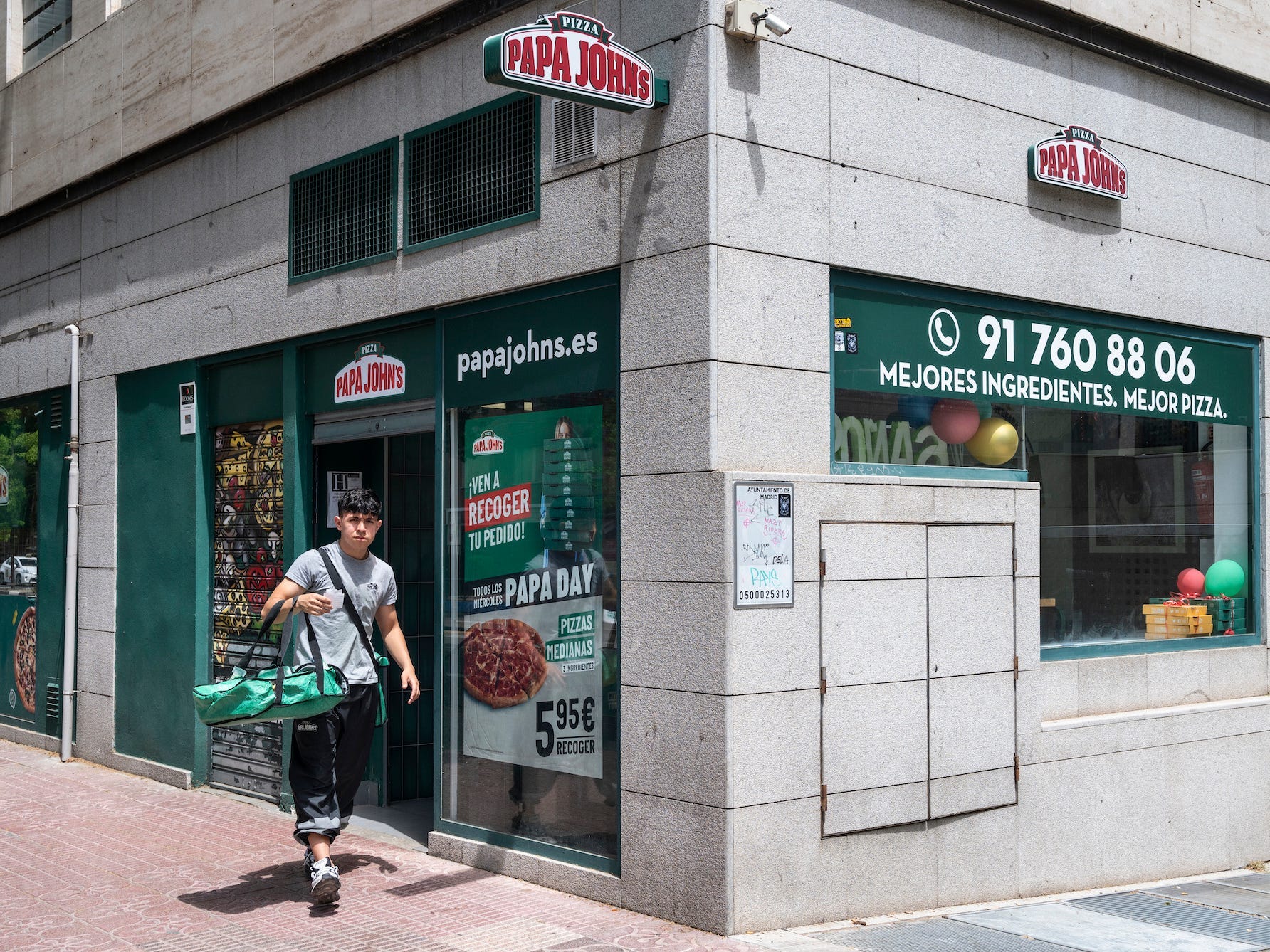 Ein Kurierarbeiter wird gesehen, wie er eine Bestellung ausliefert, als er das amerikanische Pizza-Restaurant-Franchise Papa John's Pizza in Spanien verlässt.
