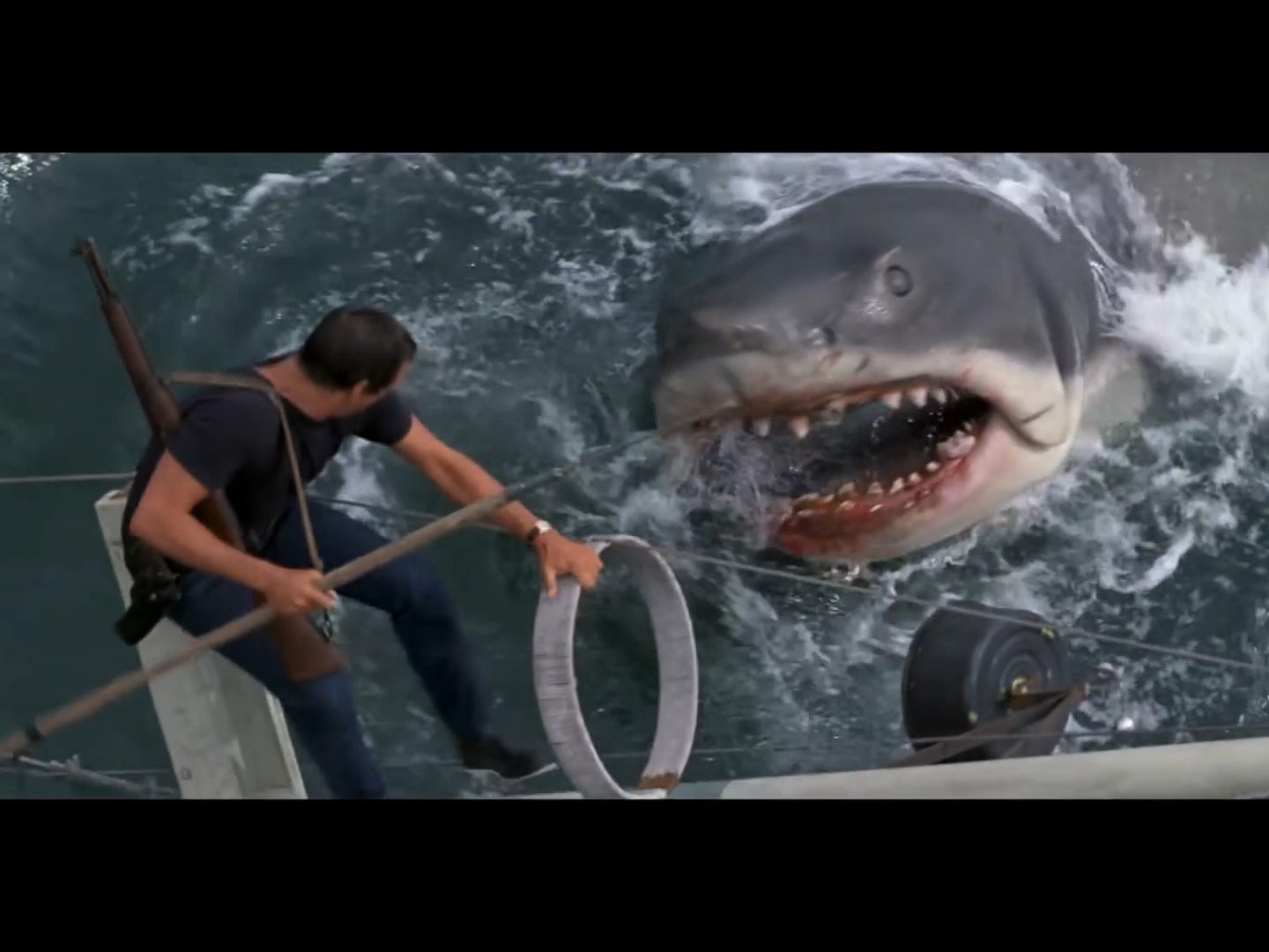 Der Protagonist des Films steht mit einem Speer über dem animatronischen Hai.