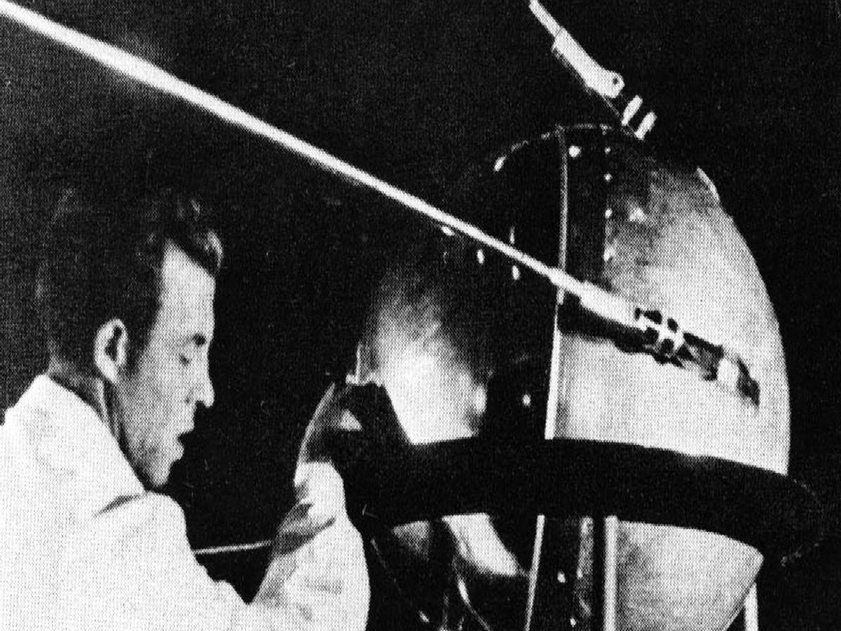 ein schwarz-weiß-foto zeigt einen mann im laborkittel vor dem sputnik-satelliten