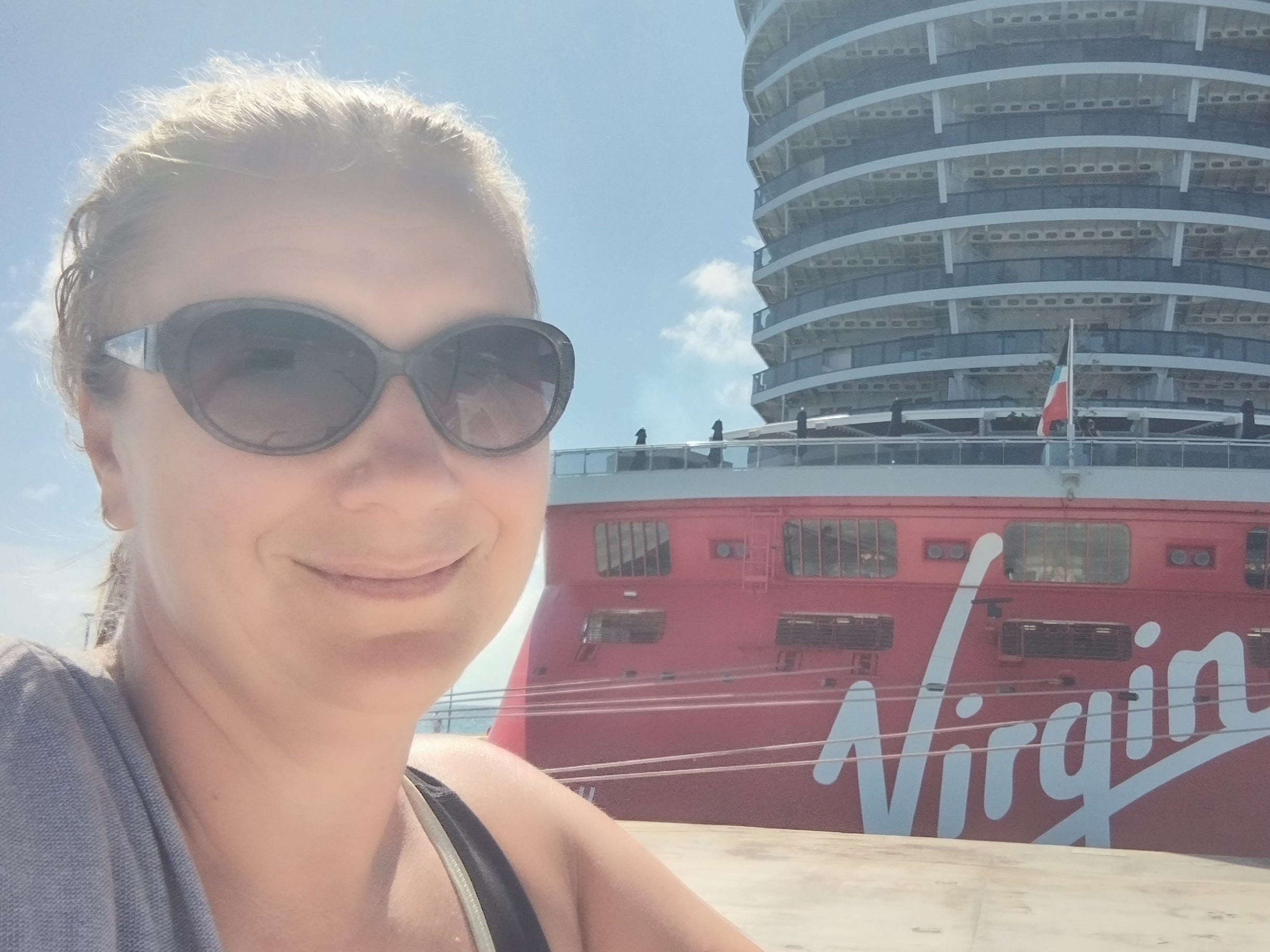 Frau mit schwarzer Sonnenbrille, die ein Selfie mit Virgin Voyages Cruise macht