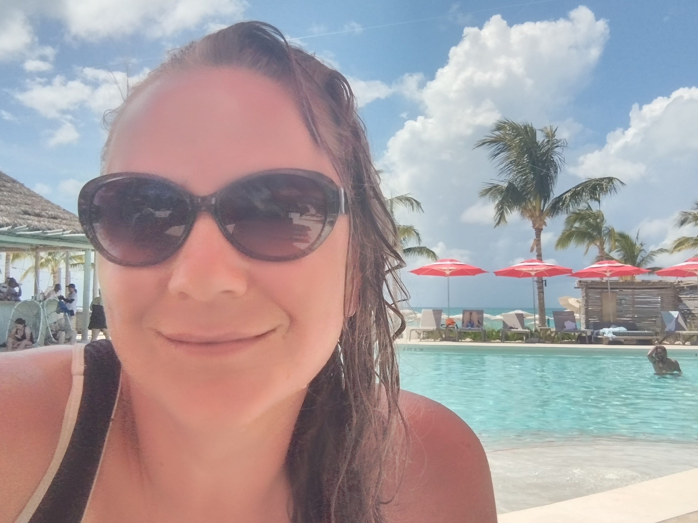 Frau mit schwarzer Sonnenbrille lächelt für ein Selfie in einem Pool im Bimini Beach Club