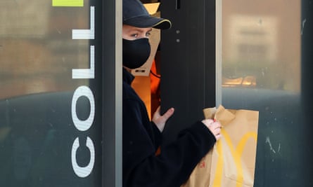 Ein Mitarbeiter trägt eine Maske, um Kunden in einem Drive-Thru von McDonald's in der Nähe von Dover in Kent zu bedienen.
