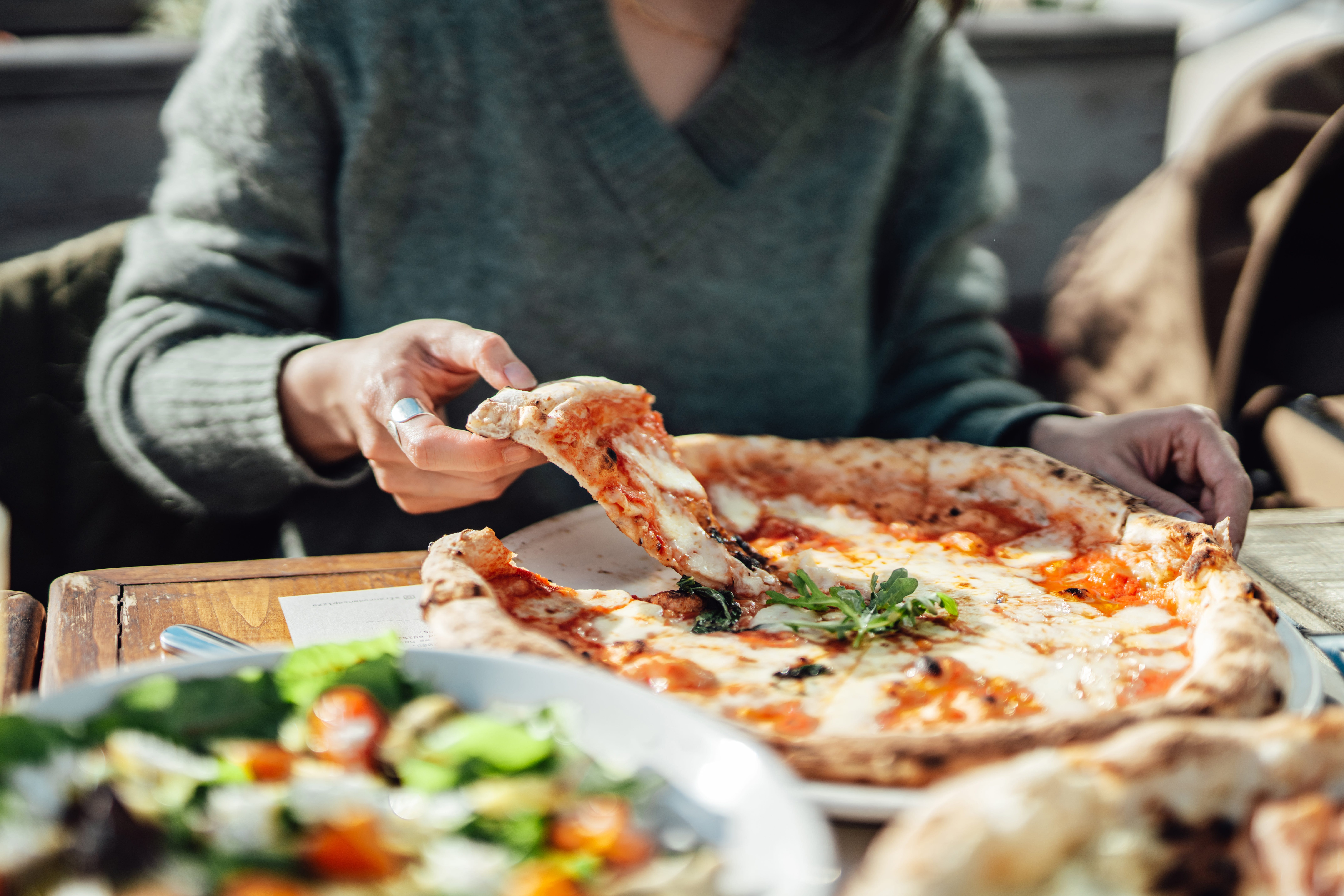 Nahaufnahme einer Frau, die Pizza in einem Restaurant genießt