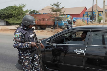 Ein nigerianischer Polizist hält am 26. Februar nach den Präsidentschafts- und Parlamentswahlen in Nigeria ein Auto an einem Sicherheitskontrollpunkt in Awka, Nigeria, an.