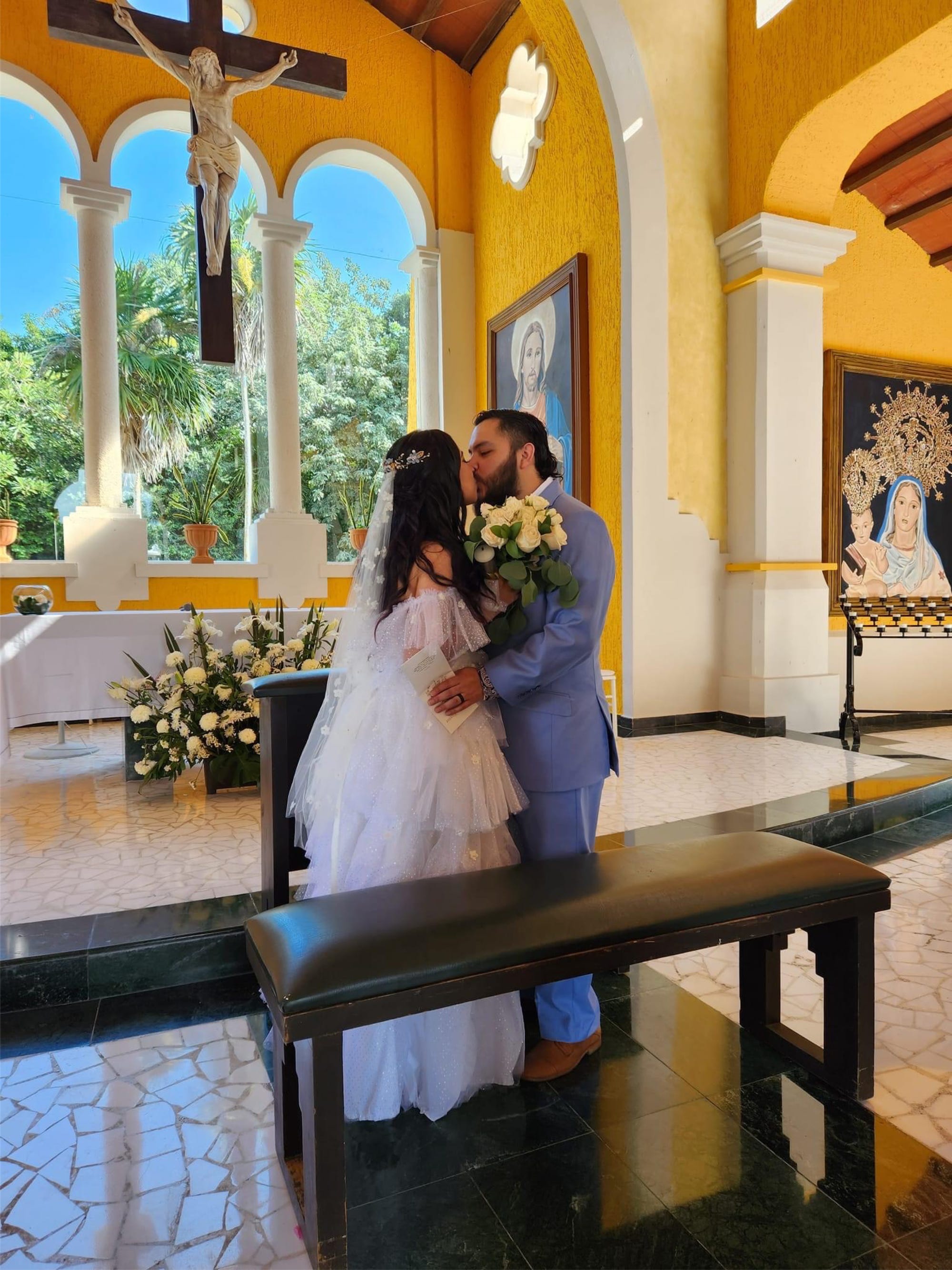 Ein Brautpaar küsst sich in einer gelben Kirche.
